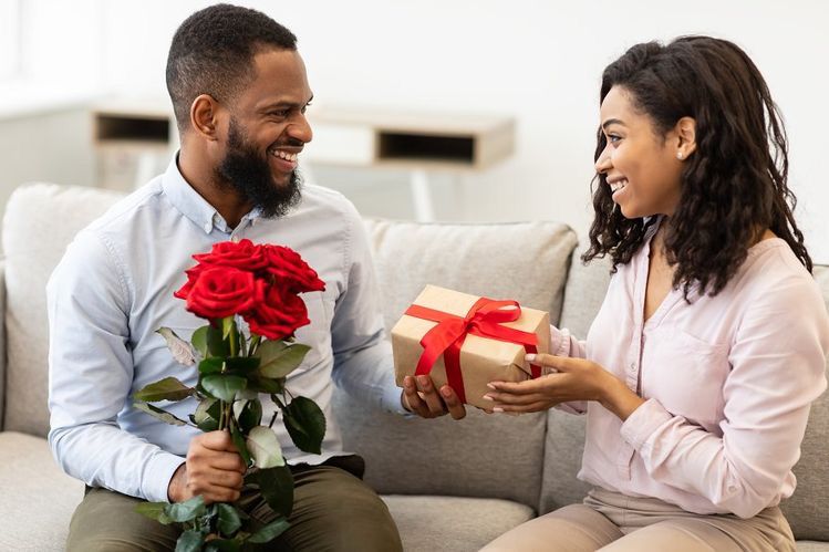 black man receiving flowers and gift from black woman