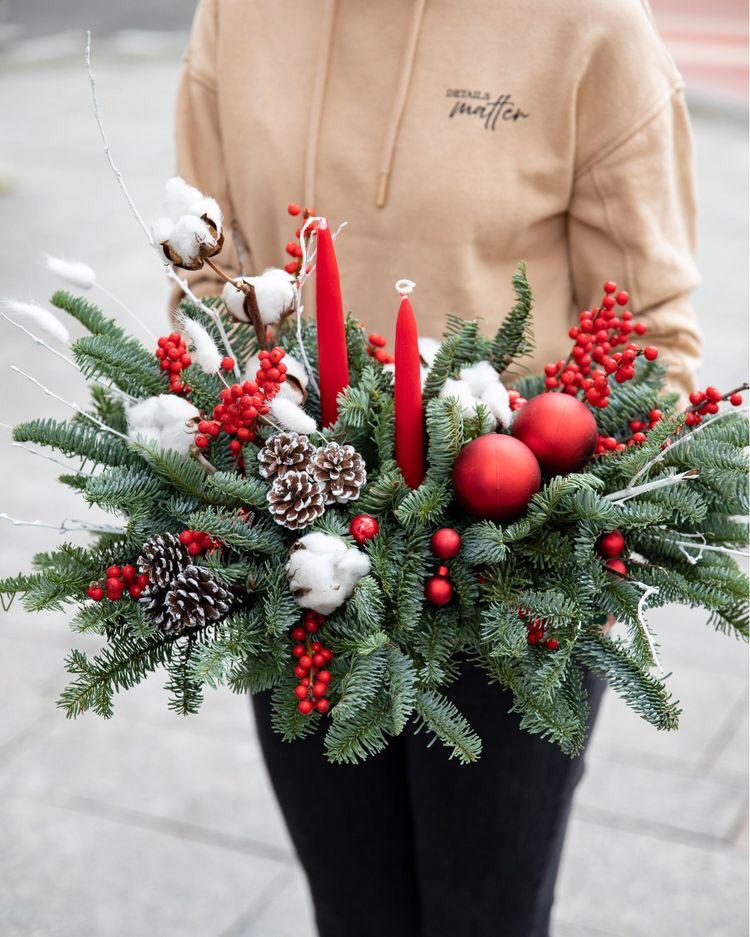 woman holding a christmas wreath with candles in it